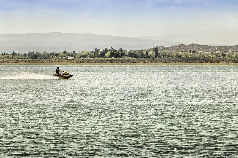 在阿根廷门多萨里瓦达维亚的El Carrizal大坝上行走的水上摩托艇。